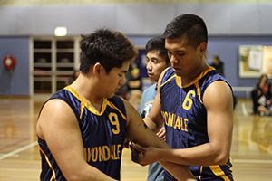 Mark Singh tapes a black band to the arm of Kenneth Lozada before the Rookies versus Returns All-Star game. Credit: Annalise Lindsay.
